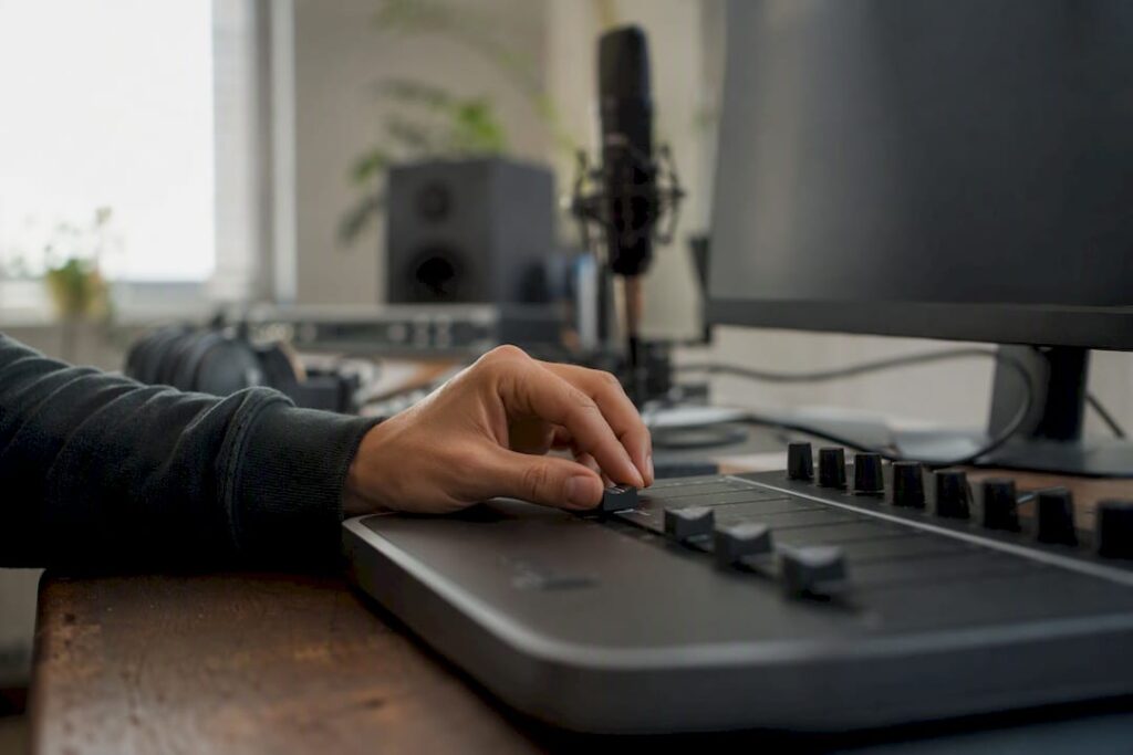 Hand die schuifregelaar van DAW-controller in studio bedient