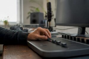 Hand die schuifregelaar van DAW-controller in studio bedient